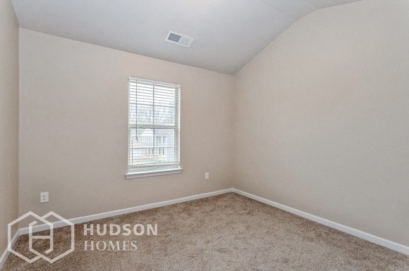 a bedroom with a window and a carpeted floor