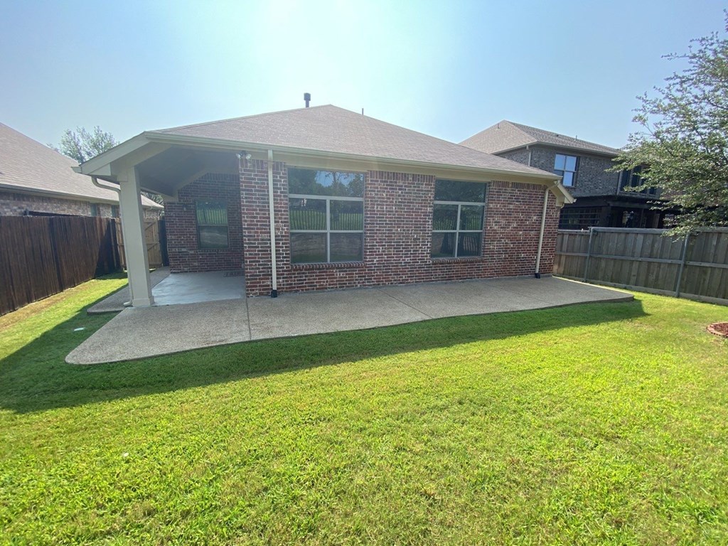 a backyard with a patio and a brick house