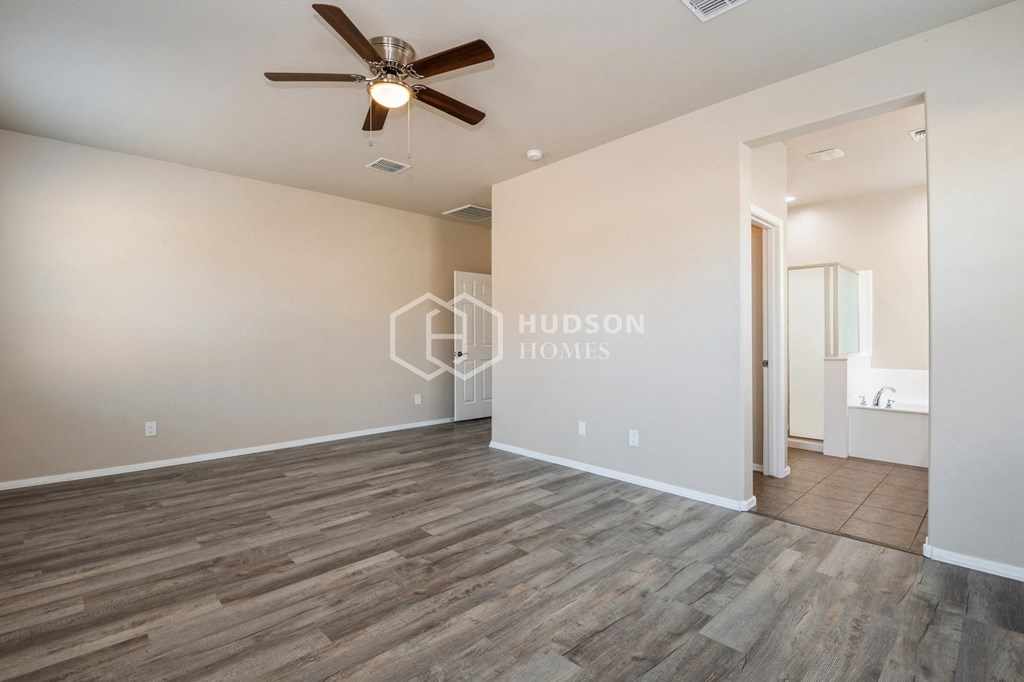 a large living room with wood floors and a ceiling fan