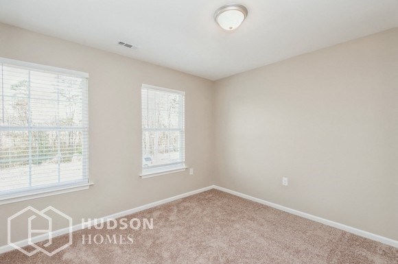 a bedroom with two windows and a carpeted floor