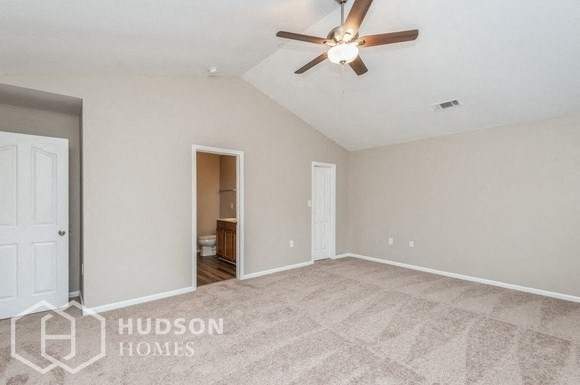 an empty living room with a ceiling fan and a door to a bathroom