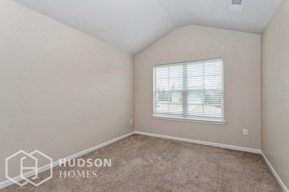 a bedroom with a window and a carpeted floor