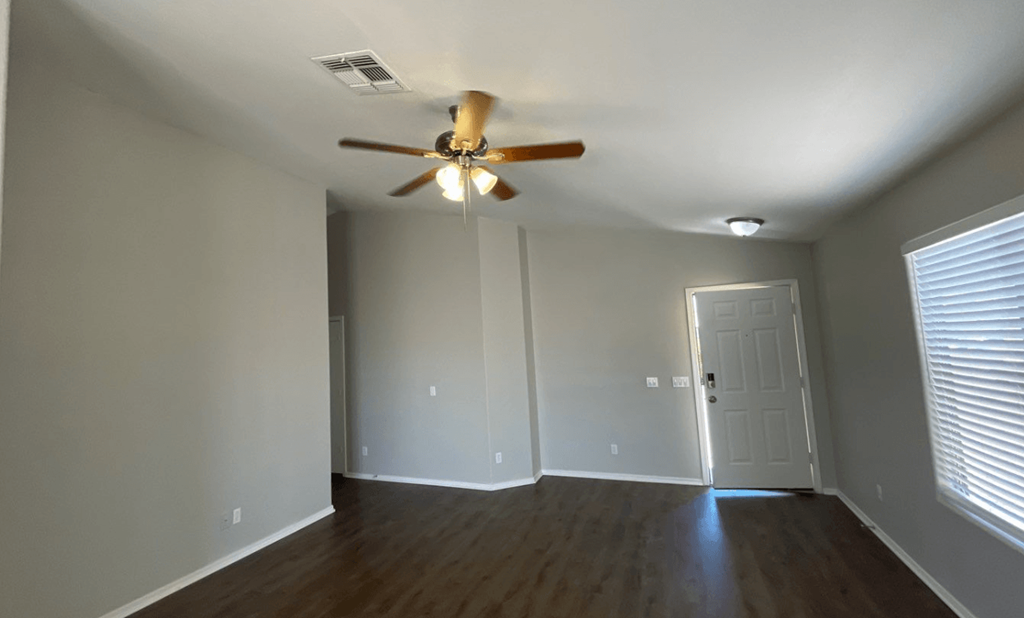 an empty living room with a ceiling fan
