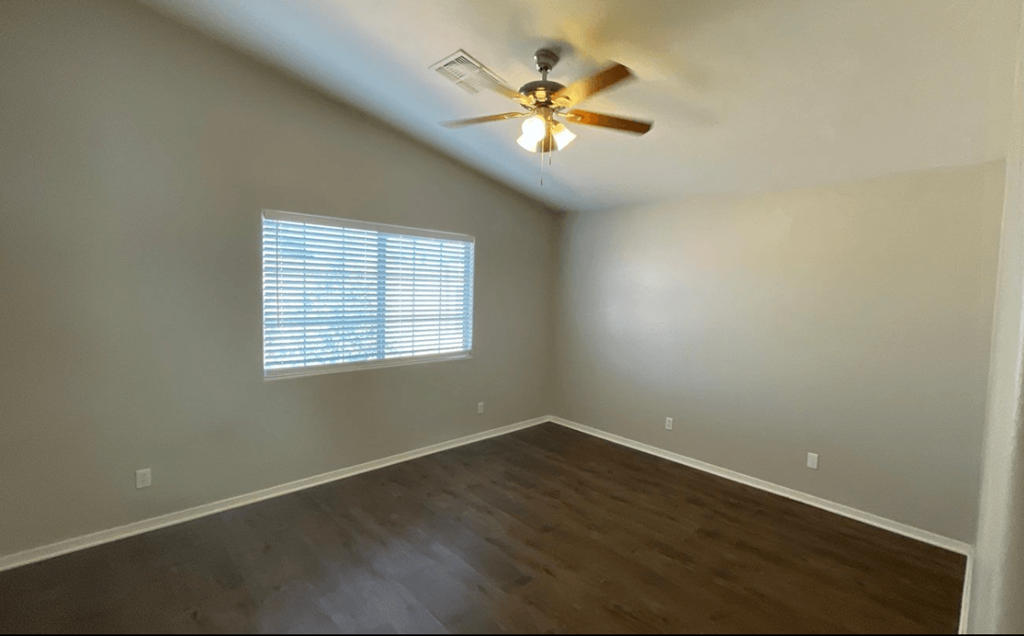 an empty living room with a ceiling fan and a window