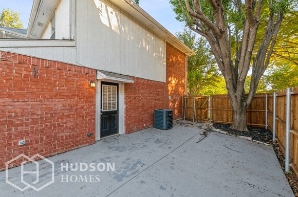 a brick house with a backyard with a tree and a fence