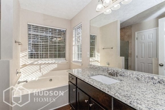 a bathroom with a sink and a mirror and a tub