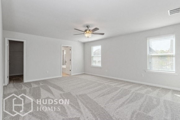 an empty living room with a ceiling fan and a door to a hallway
