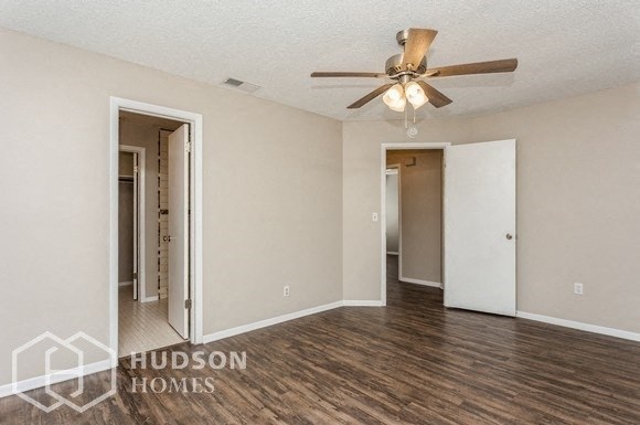 a living room with a ceiling fan and a door to a hallway