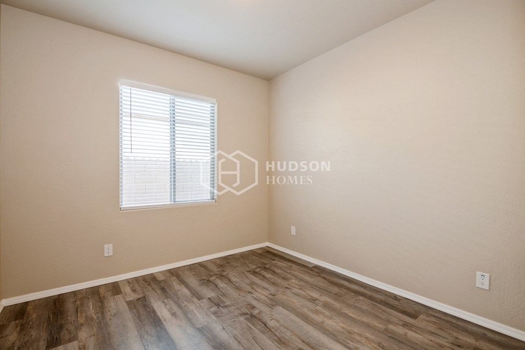 a bedroom with a hard wood floor and a window