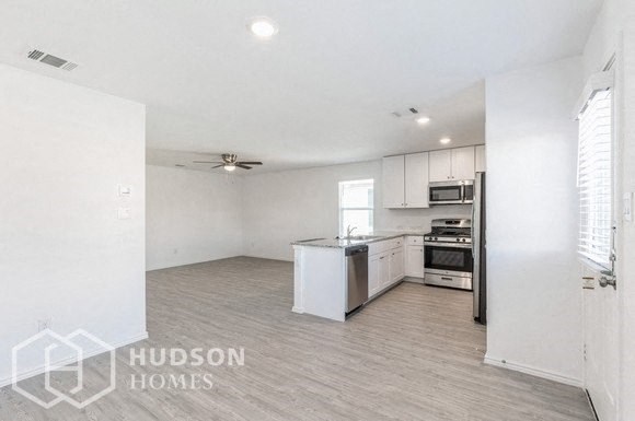 an empty kitchen with white cabinets and a stove and refrigerator