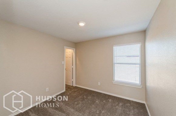 a bedroom with a carpeted floor and a window and a door