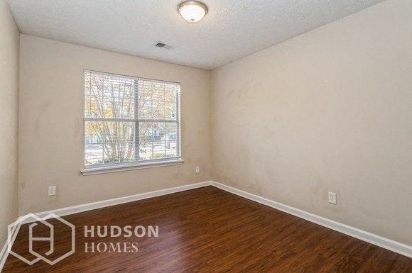 an empty living room with a window and wood floors