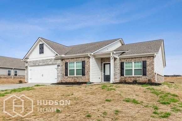 a white and brick house with green shutters and a blue sky