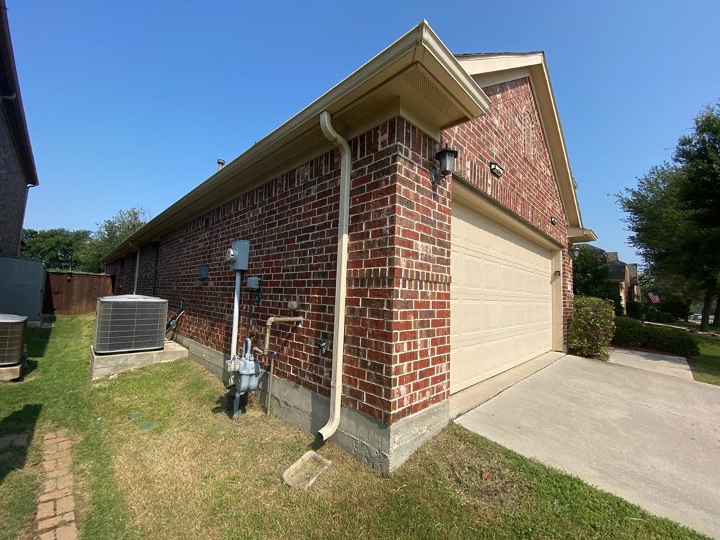 the side of a brick house with a garage door