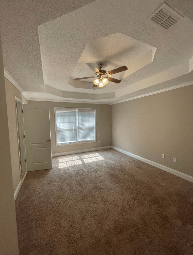 an empty living room with a ceiling fan and a window