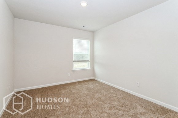 a bedroom with white walls and a window and a carpet