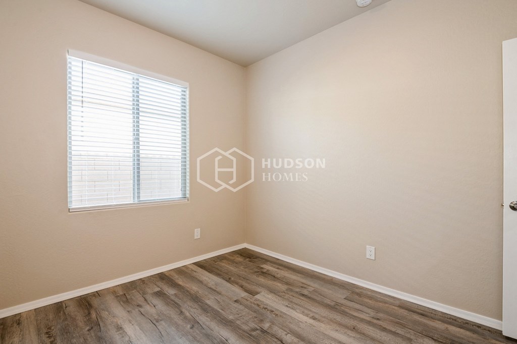a bedroom with a wood floor and a window