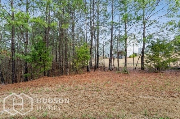 a wooded area with pine trees and a house in the distance