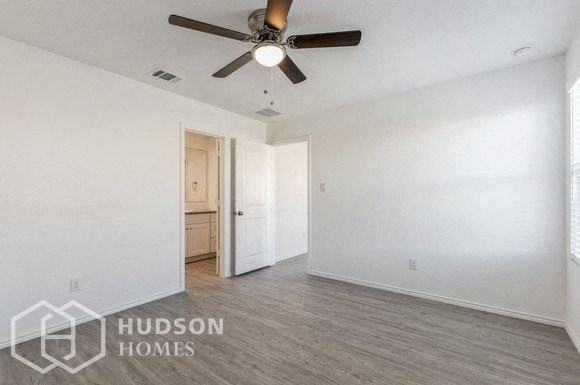 an empty living room with a ceiling fan and white walls