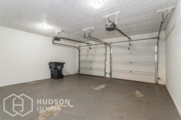 the inside of a garage with two garage doors and a trash can
