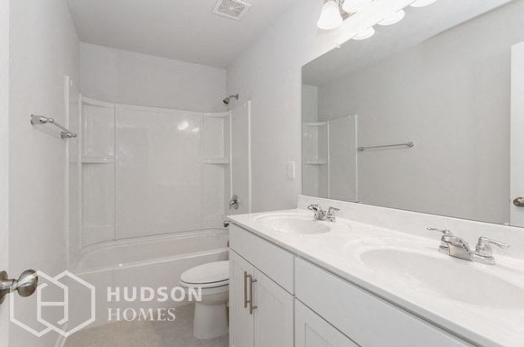 a white bathroom with two sinks and a shower and a toilet