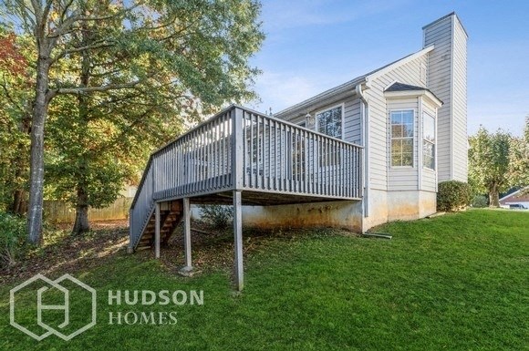 a small white house with a deck on a lawn