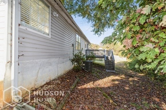 the side of a house with a deck and a tree