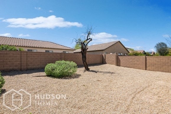a backyard with a retaining wall and a tree in the gravel