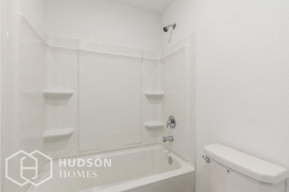 a white bathroom with a bath tub and a toilet