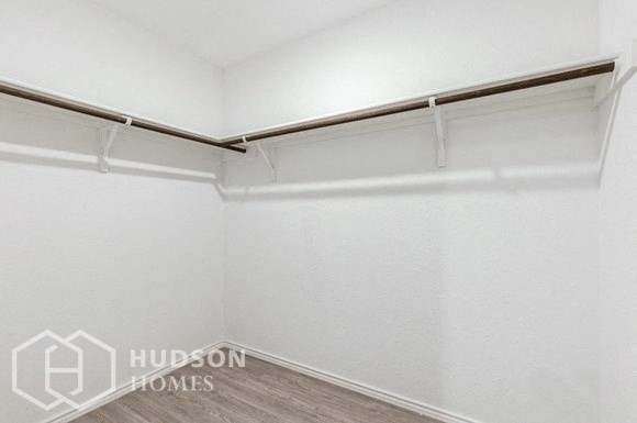 a white room with white walls and a white curtain rail and a wood floor