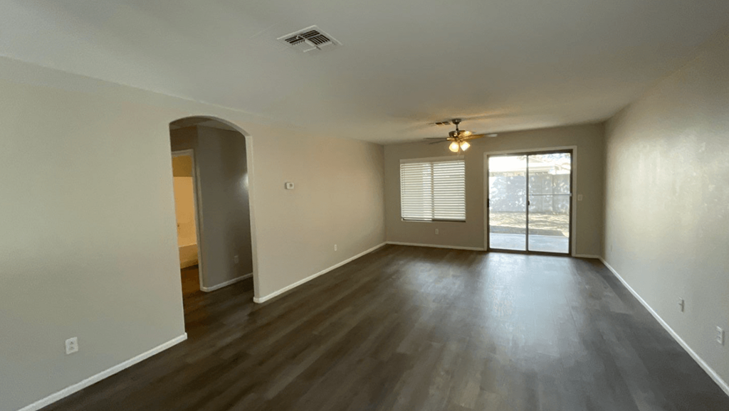 an empty living room with wood flooring and a ceiling fan