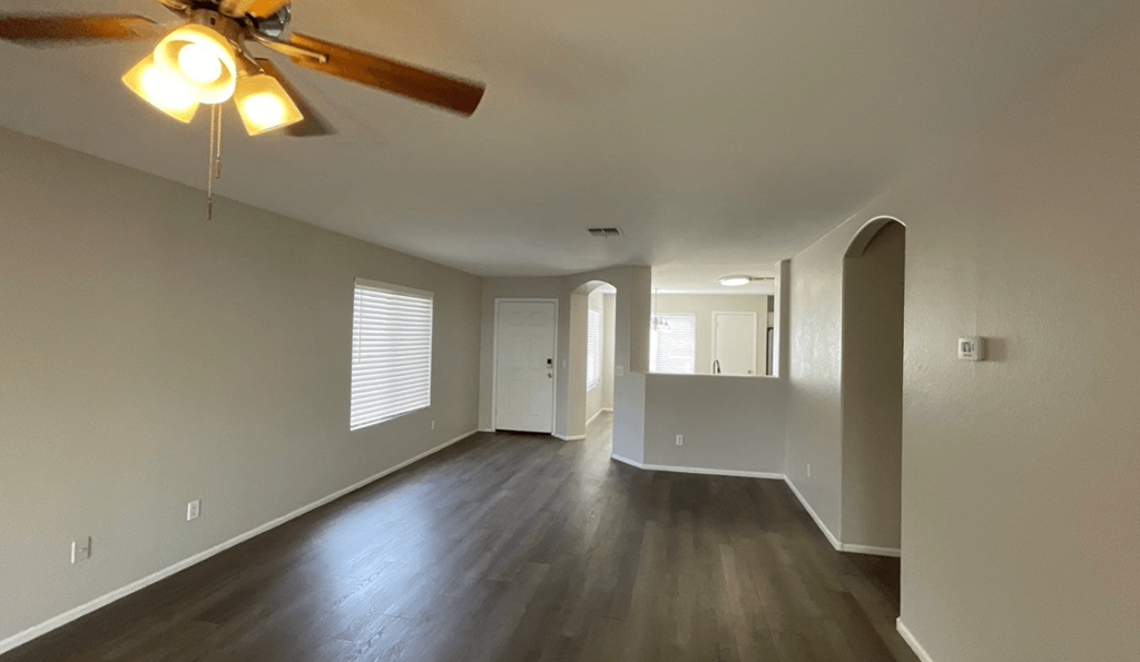 an empty living room with wood floors and a ceiling fan