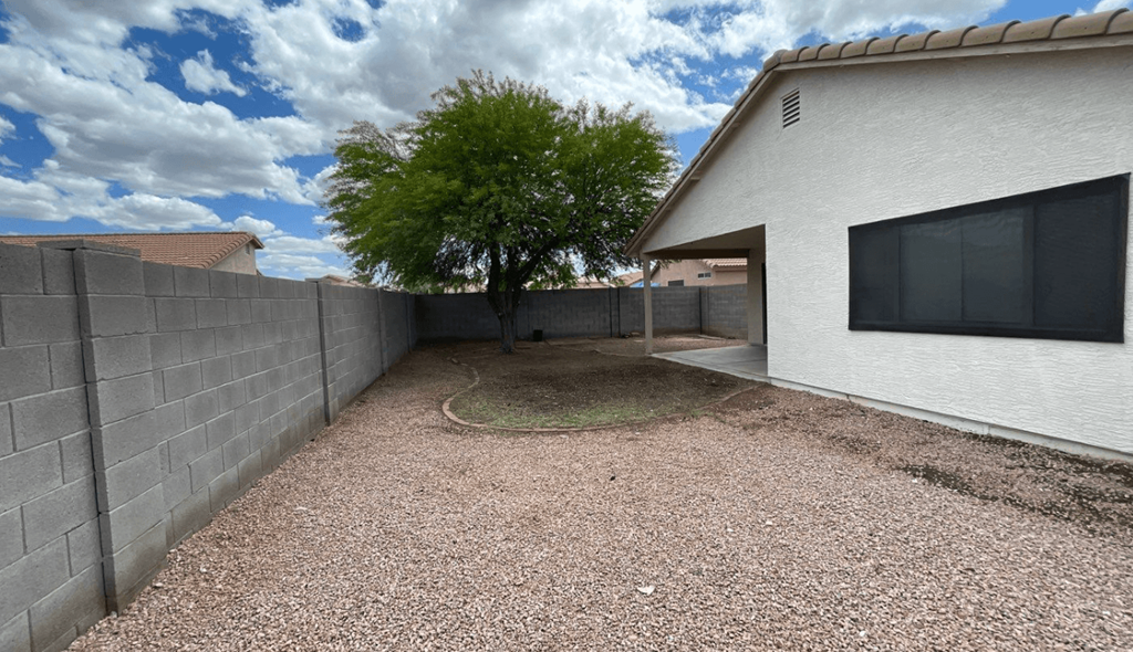 a backyard with a tree and a white house