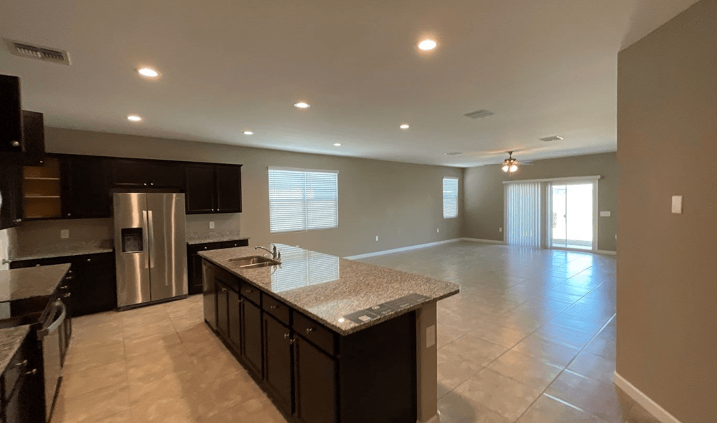an empty kitchen and living room with a marble counter top