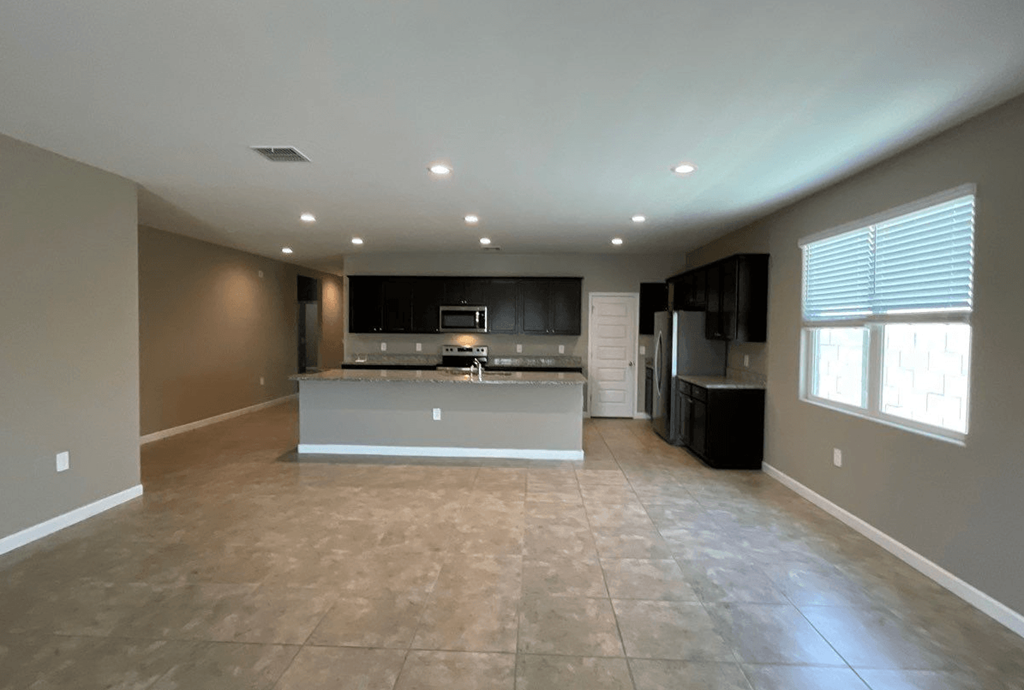 an empty living room and kitchen with a large window