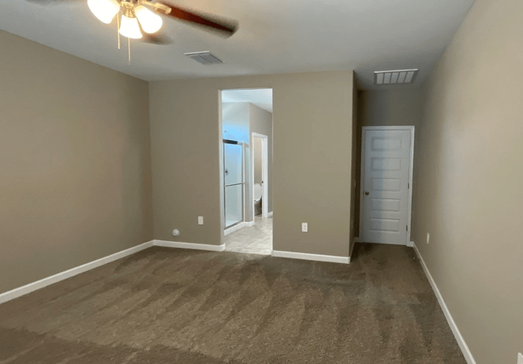 an empty living room with carpet and a ceiling fan