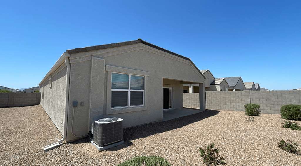 a small gray house with a trash can in front of it
