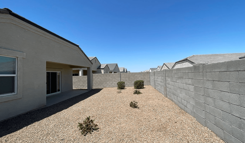 a row of houses with concrete walls and a gravel yard