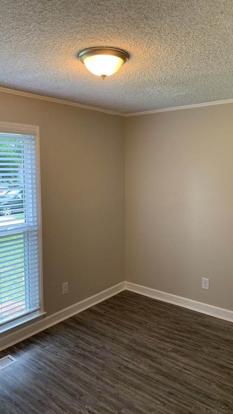 an empty room with a window and a lamp on the ceiling