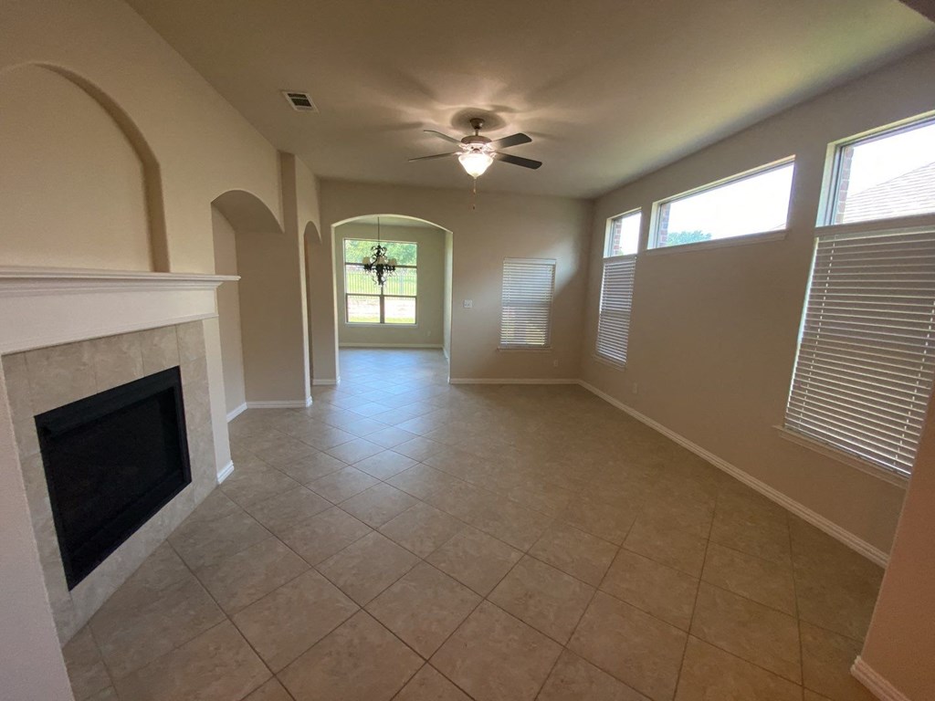 an empty living room with a fireplace and a ceiling fan