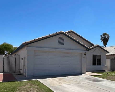 a white house with a garage door and a palm tree