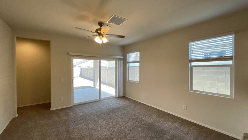 an empty living room with a ceiling fan and a door to a patio