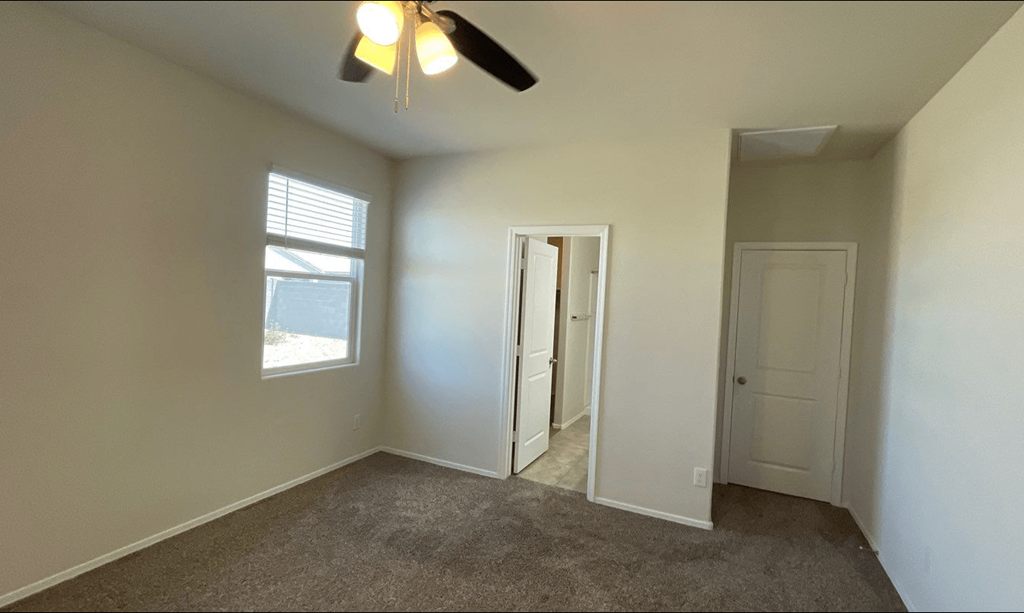an empty room with a ceiling fan and a window
