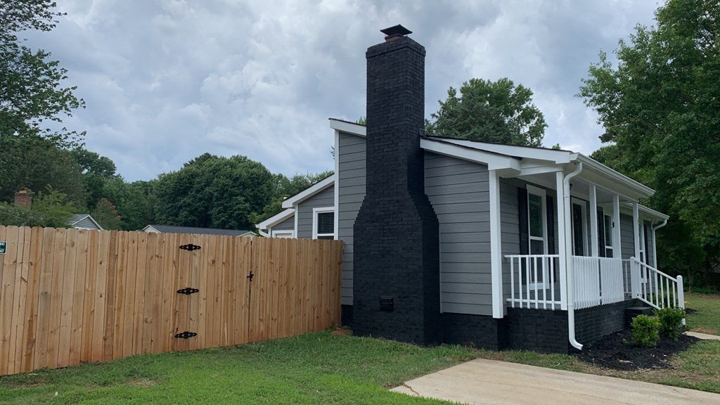 a house with a fence and a chimney on the side of it