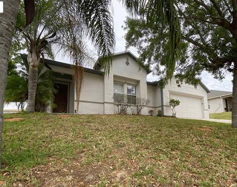 a house with a lawn and trees in front of it