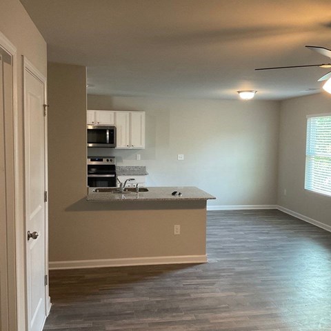 an empty kitchen and living room with a microwave and a sink