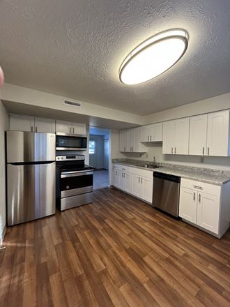a kitchen with white cabinets and a wooden floor