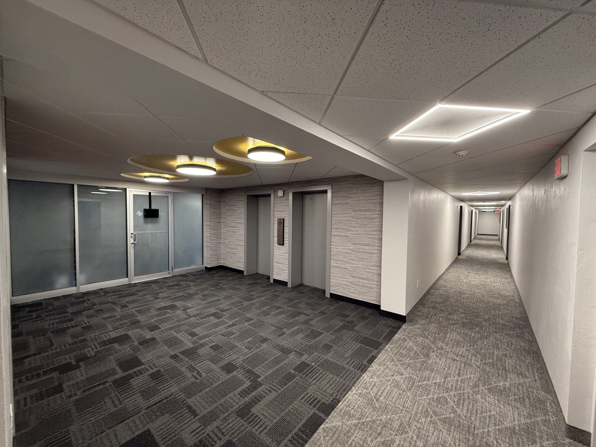 A long hallway with carpeted floors and doors on both sides.