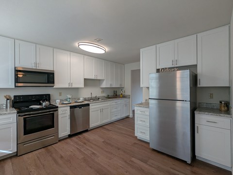 A kitchen with white cabinets and a stainless steel refrigerator.