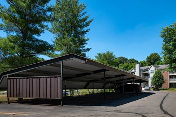 A large brown building with a grey roof is surrounded by trees at Belmont Ridge Apartments, Monroeville, PA, 15146